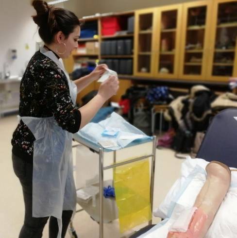 Une étudiante infirmière fait un pansement en salle de travaux pratiques